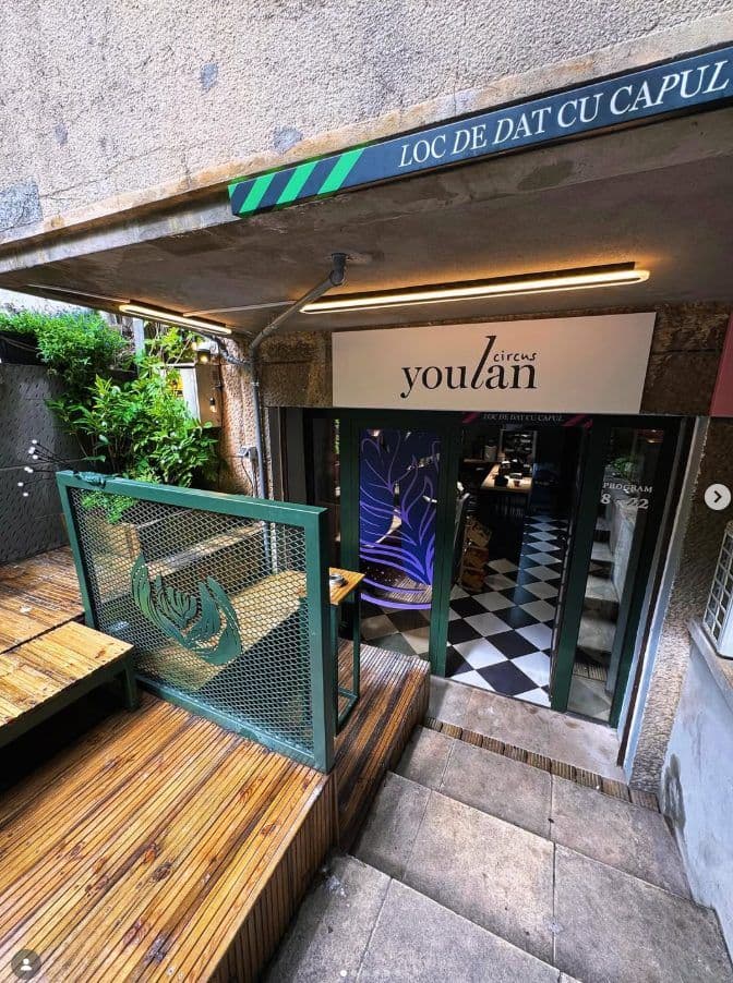 Intrarea în cafenea, cu treptele de piatră și ușile verzi