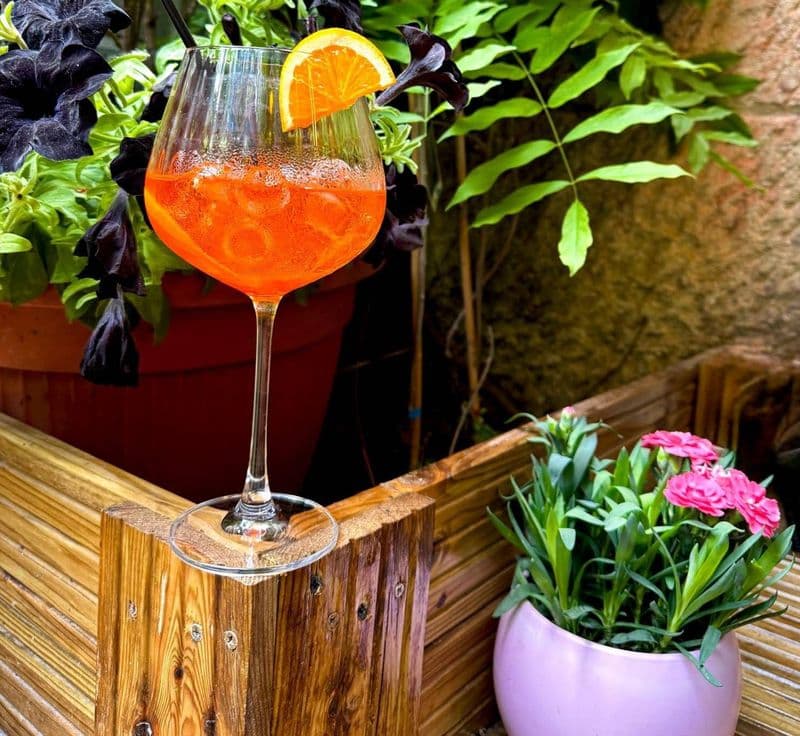 Pahar de Aperol Spritz cu felie de portocală pe terasă